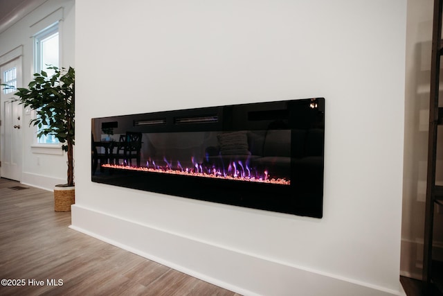 interior details with baseboards, a glass covered fireplace, and wood finished floors