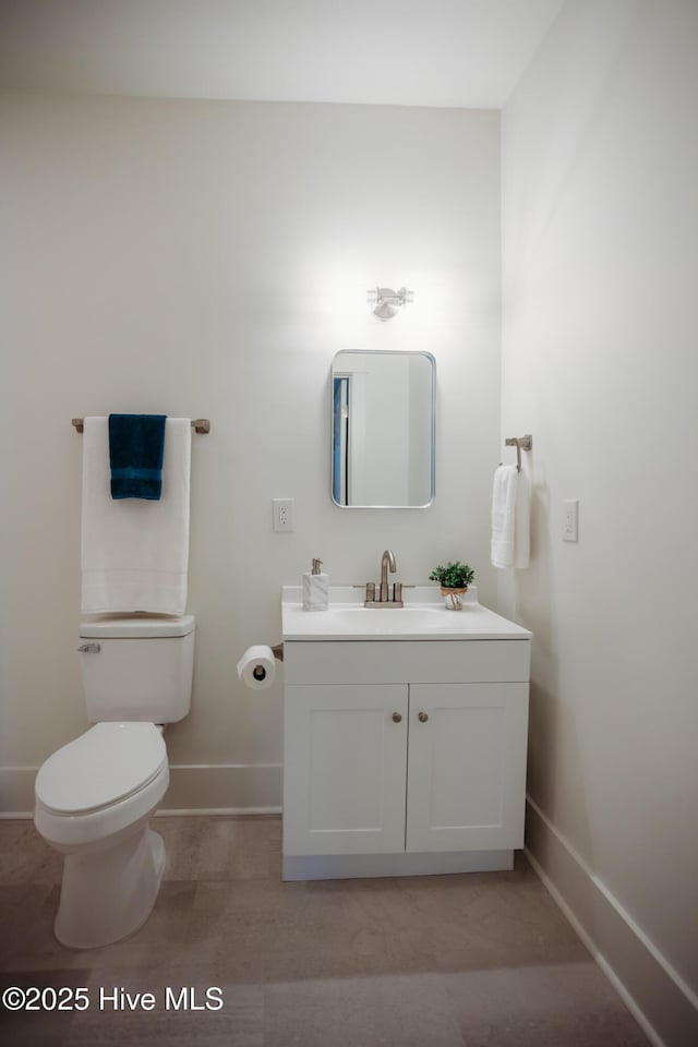 bathroom featuring toilet, baseboards, and vanity