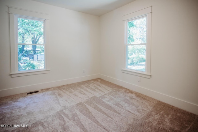 carpeted empty room with baseboards, visible vents, and a healthy amount of sunlight