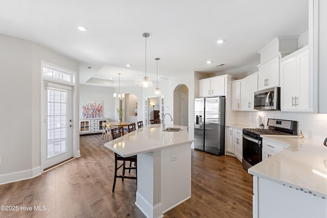 2226 Jasper Forest Trl, Winnabow, NC 28479 - kitchen with appliances with stainless steel finishes, arched walkways, dark wood finished floors, a kitchen breakfast bar, and backsplash