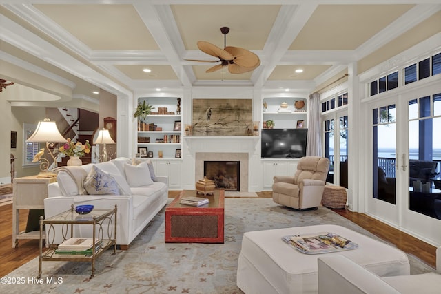 living area with a ceiling fan, built in features, wood finished floors, and coffered ceiling