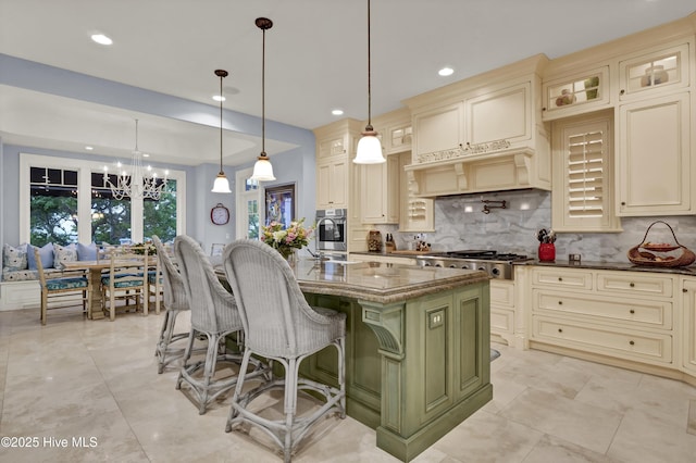 kitchen featuring dark stone counters, appliances with stainless steel finishes, cream cabinets, and decorative backsplash