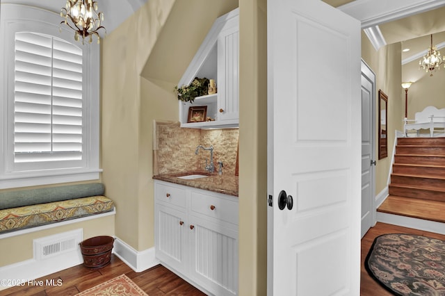 interior space featuring an inviting chandelier, baseboards, wood finished floors, and visible vents
