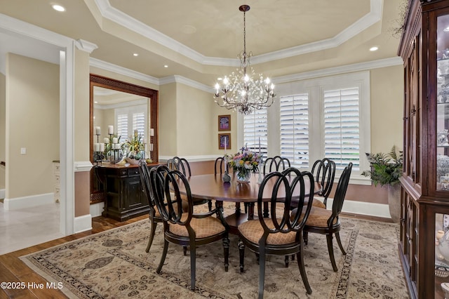 dining area featuring crown molding, a tray ceiling, a chandelier, and light wood finished floors