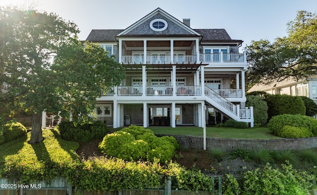 back of property featuring a chimney, stairs, and a balcony