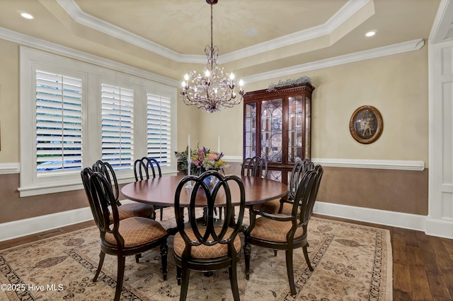 dining area featuring a raised ceiling, baseboards, hardwood / wood-style flooring, and a chandelier