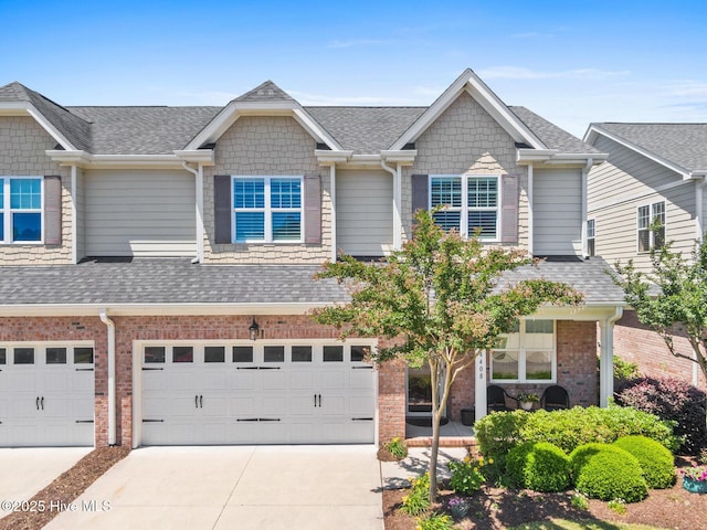 multi unit property with a shingled roof, an attached garage, and concrete driveway