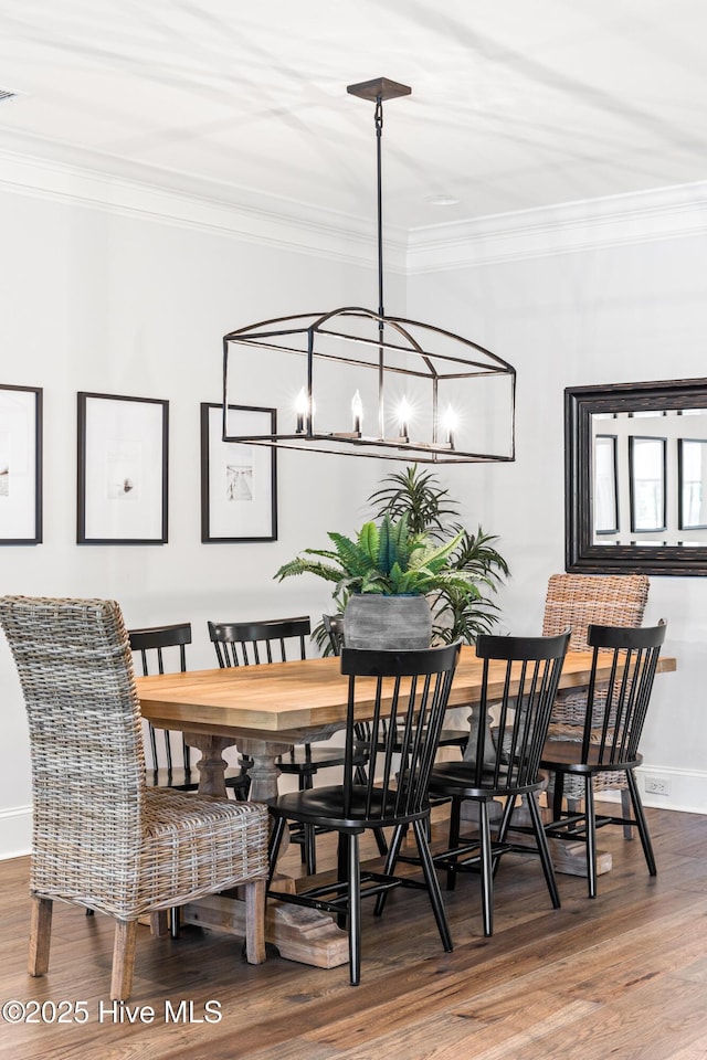 dining space with baseboards, ornamental molding, wood finished floors, and a chandelier