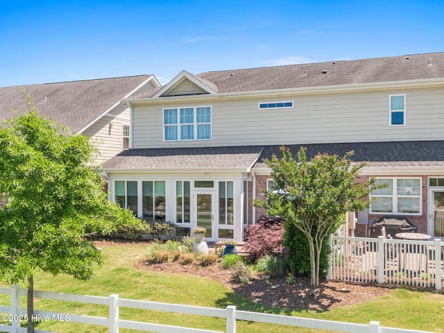rear view of house featuring fence, a shingled roof, and a yard