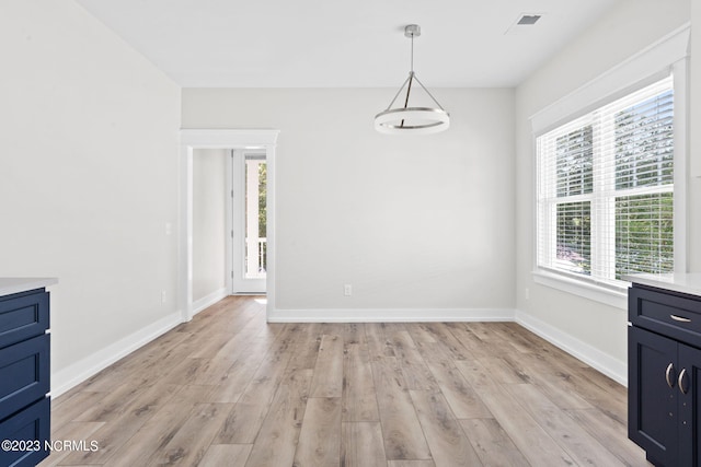 unfurnished dining area with baseboards and light wood-type flooring