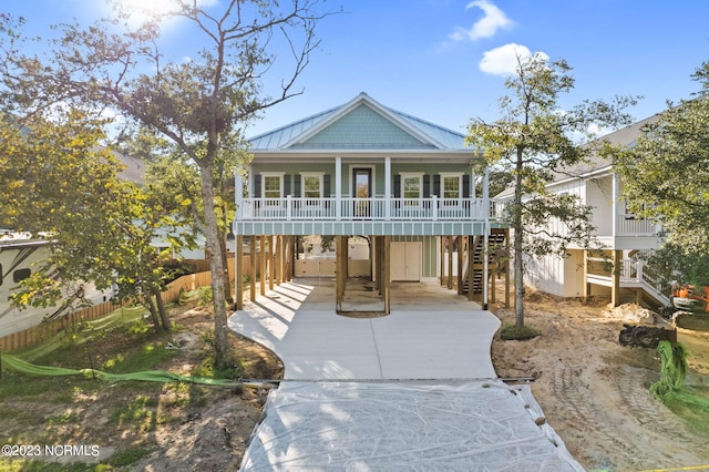 beach home featuring fence, stairs, a standing seam roof, covered porch, and metal roof