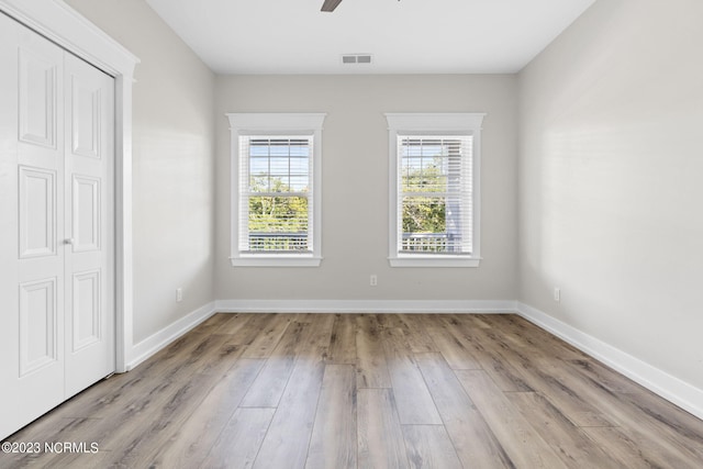unfurnished bedroom featuring visible vents, baseboards, wood finished floors, and multiple windows
