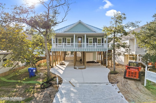 raised beach house featuring fence, stairs, a standing seam roof, covered porch, and metal roof