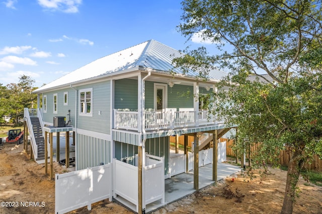 rear view of property with a patio, cooling unit, metal roof, and stairs