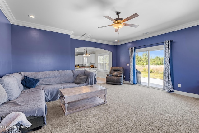 carpeted living room featuring ceiling fan with notable chandelier, crown molding, visible vents, baseboards, and arched walkways