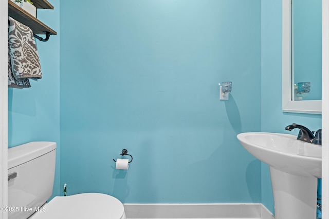 bathroom featuring toilet, baseboards, and a sink