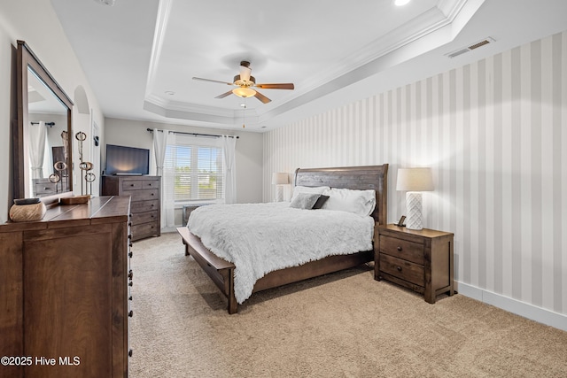 carpeted bedroom with visible vents, crown molding, a ceiling fan, a tray ceiling, and wallpapered walls