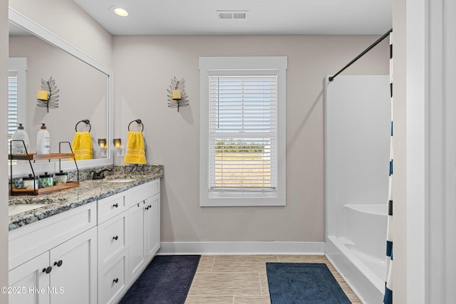 full bath with baseboards, visible vents, a sink, double vanity, and a shower