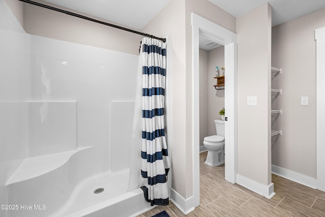 bathroom with toilet, a shower with curtain, and baseboards