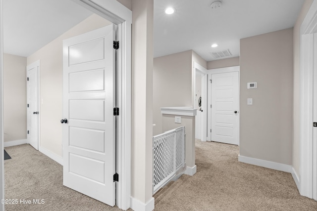 hallway featuring recessed lighting, carpet, baseboards, visible vents, and an upstairs landing