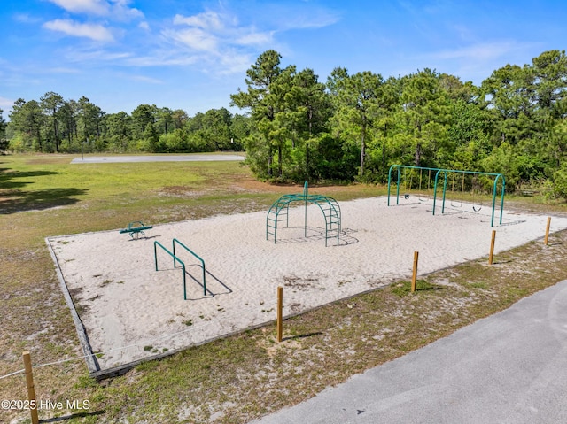 view of home's community featuring playground community, a wooded view, and a yard