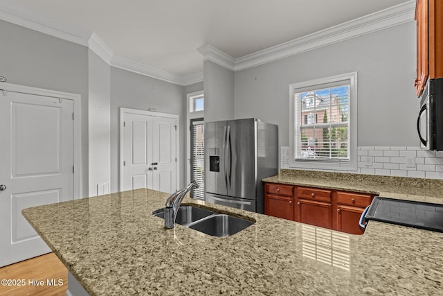 kitchen with stainless steel fridge, a sink, black microwave, ornamental molding, and light stone countertops