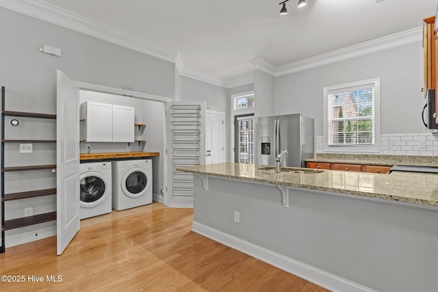 kitchen with washing machine and dryer, stainless steel refrigerator with ice dispenser, a sink, decorative backsplash, and black microwave