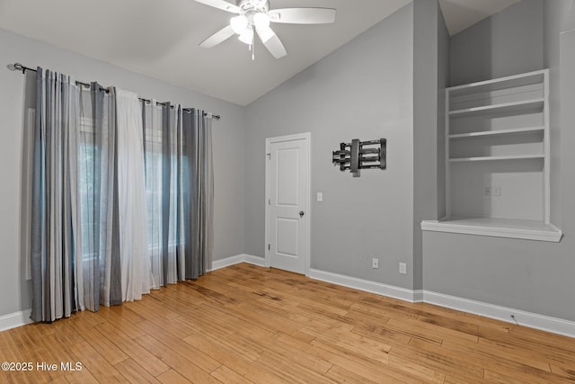 unfurnished room with lofted ceiling, a ceiling fan, light wood-type flooring, and baseboards