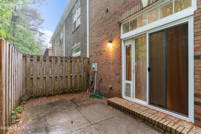 view of property exterior with brick siding, a patio, and a fenced backyard