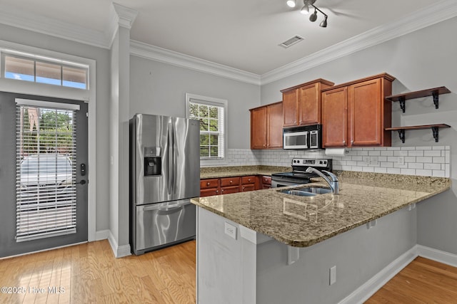 kitchen featuring stainless steel appliances, open shelves, a peninsula, light stone countertops, and a sink