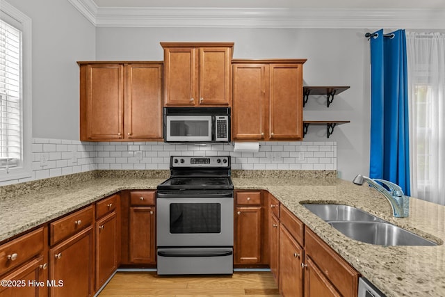 kitchen featuring stainless steel appliances, a sink, open shelves, crown molding, and plenty of natural light
