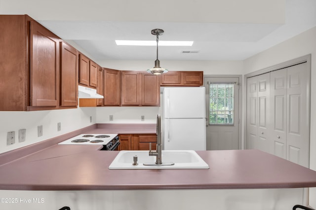 kitchen featuring a sink, range with electric cooktop, freestanding refrigerator, a peninsula, and under cabinet range hood
