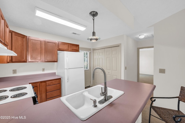 kitchen featuring visible vents, a sink, brown cabinetry, and white appliances