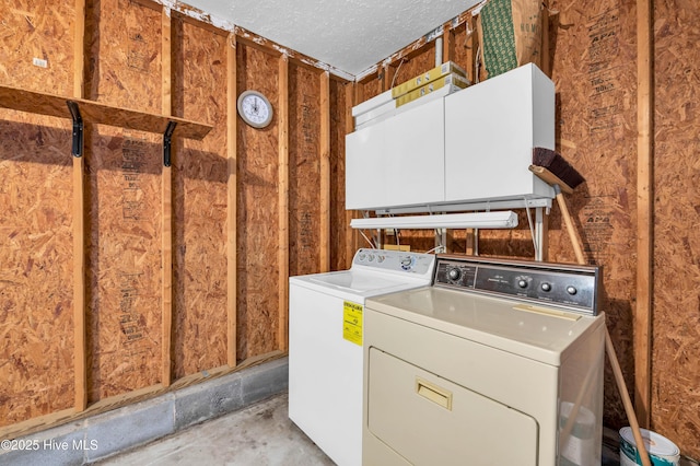washroom with laundry area, a textured ceiling, and washer and clothes dryer