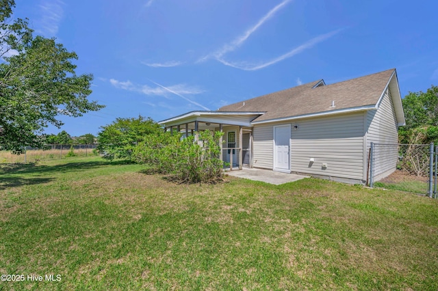 rear view of property featuring a lawn, fence, a shingled roof, and a patio area