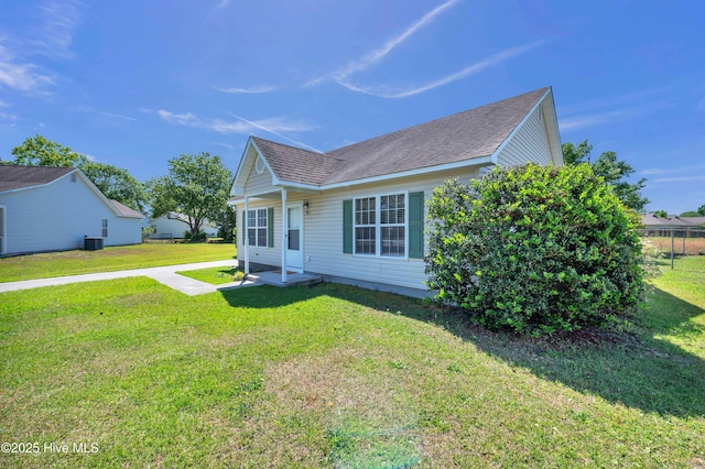 view of front of property featuring roof with shingles, central air condition unit, and a front yard