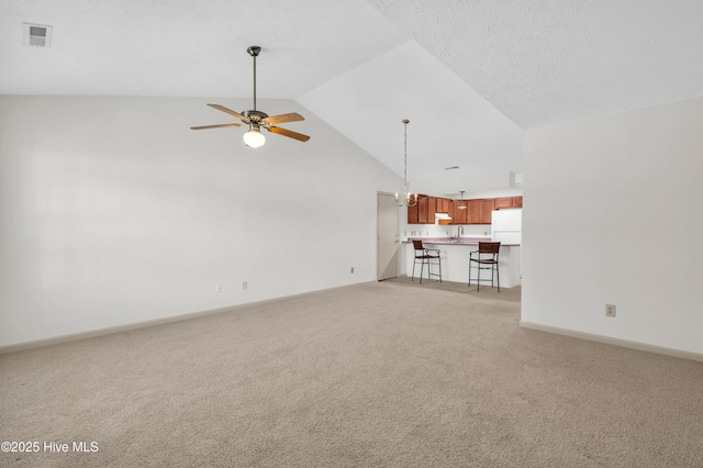 unfurnished living room featuring visible vents, baseboards, ceiling fan, high vaulted ceiling, and light colored carpet