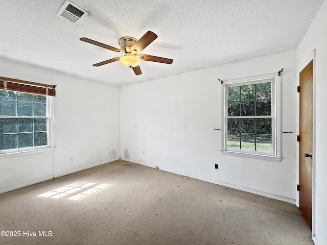 spare room featuring healthy amount of natural light, ceiling fan, a textured ceiling, carpet flooring, and baseboards