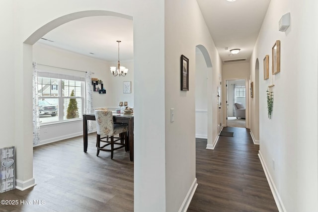 603 Coral Reef Ct, Sneads Ferry, NC 28460 - hallway featuring an inviting chandelier, baseboards, arched walkways, and dark wood finished floors