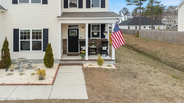 603 Coral Reef Ct, Sneads Ferry, NC 28460 - property entrance with a yard, a porch, fence, and a shingled roof