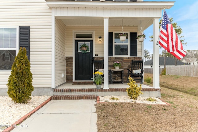 603 Coral Reef Ct, Sneads Ferry, NC 28460 - doorway to property featuring stone siding, fence, and covered porch
