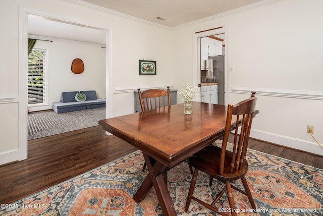 dining area featuring baseboards, visible vents, wood finished floors, and ornamental molding
