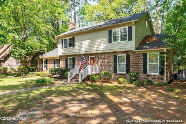 view of front of house with a front lawn, a chimney, and brick siding