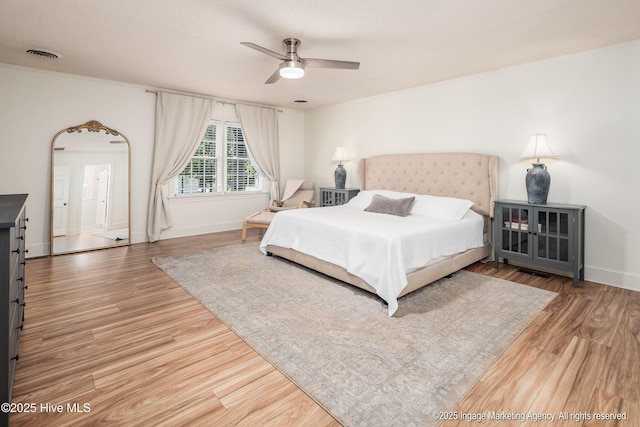 bedroom featuring wood finished floors, a ceiling fan, visible vents, and baseboards
