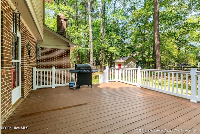 deck featuring a grill, a storage unit, and an outbuilding