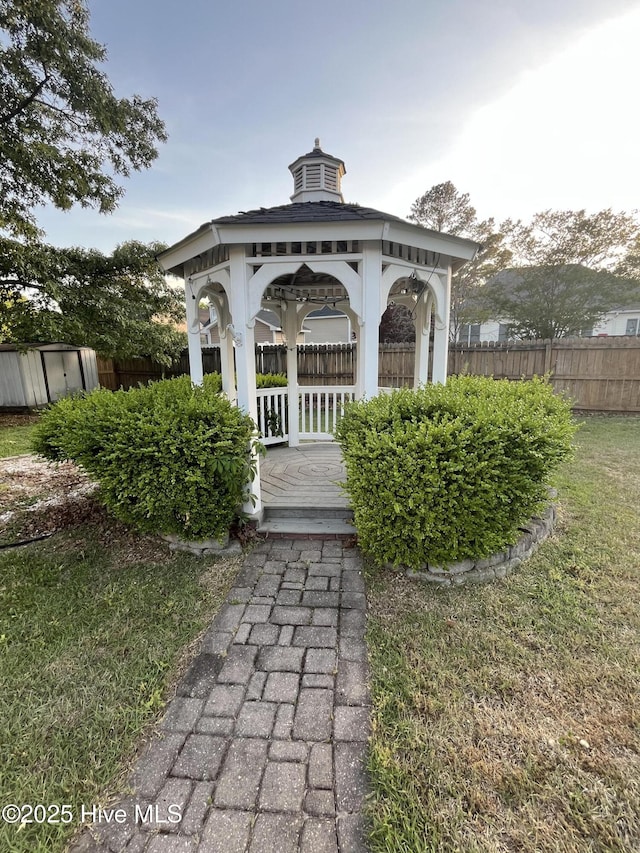 view of home's community with a gazebo, fence, an outdoor structure, a storage unit, and a yard