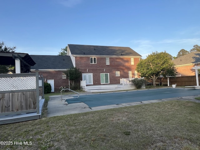 rear view of property featuring a patio, a lawn, fence, and a fenced in pool