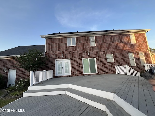 back of house featuring french doors, a wooden deck, and brick siding