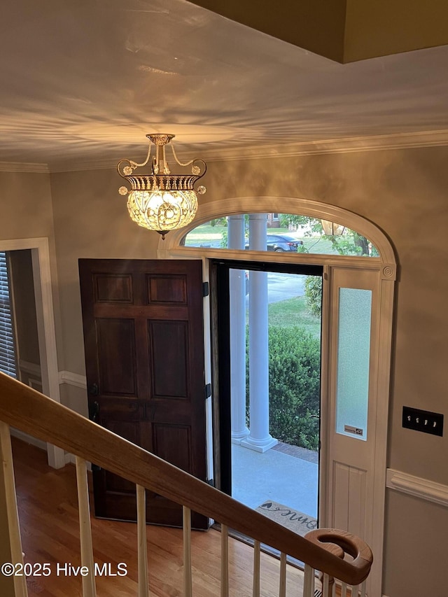 foyer featuring crown molding, wood finished floors, and an inviting chandelier