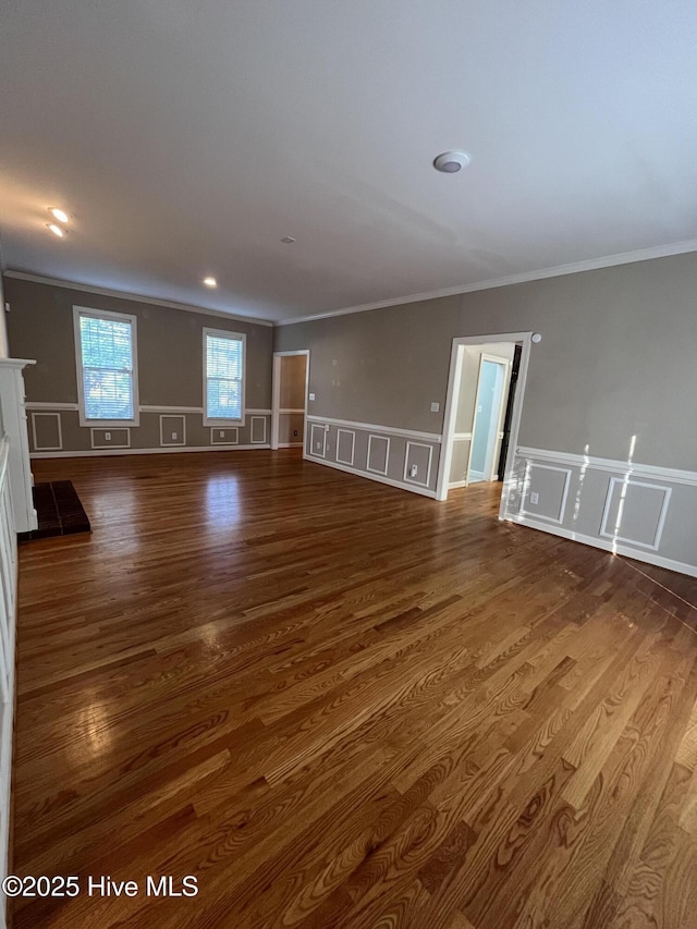 unfurnished living room with ornamental molding, a decorative wall, and dark wood-type flooring
